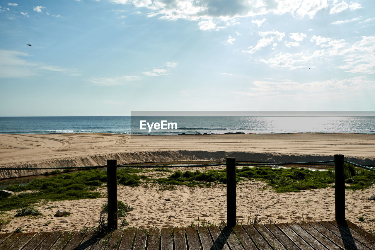 WOODEN POSTS ON SEA AGAINST SKY