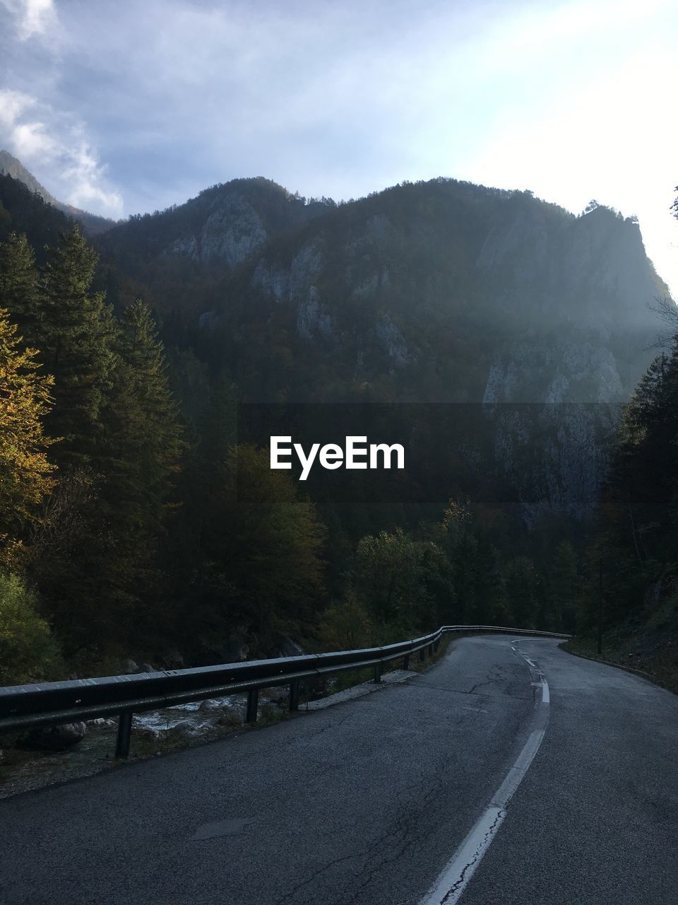 Road amidst trees and mountains against sky