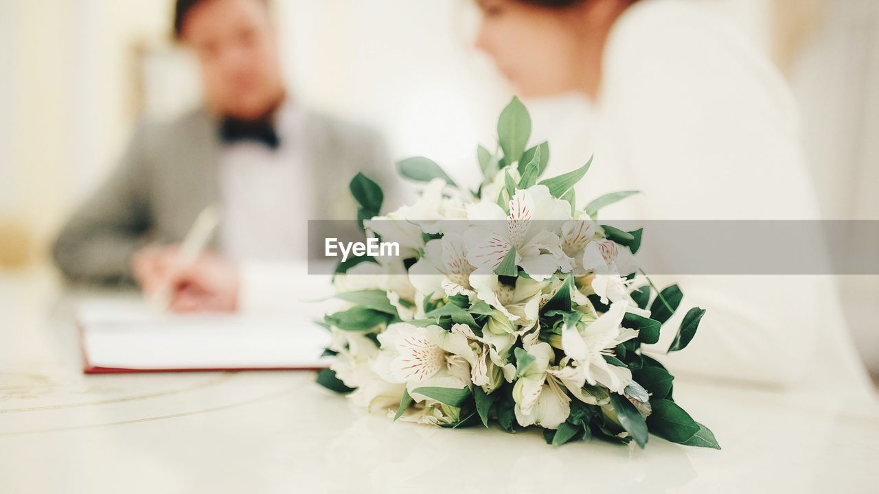 Close-up of rose bouquet with couple at table