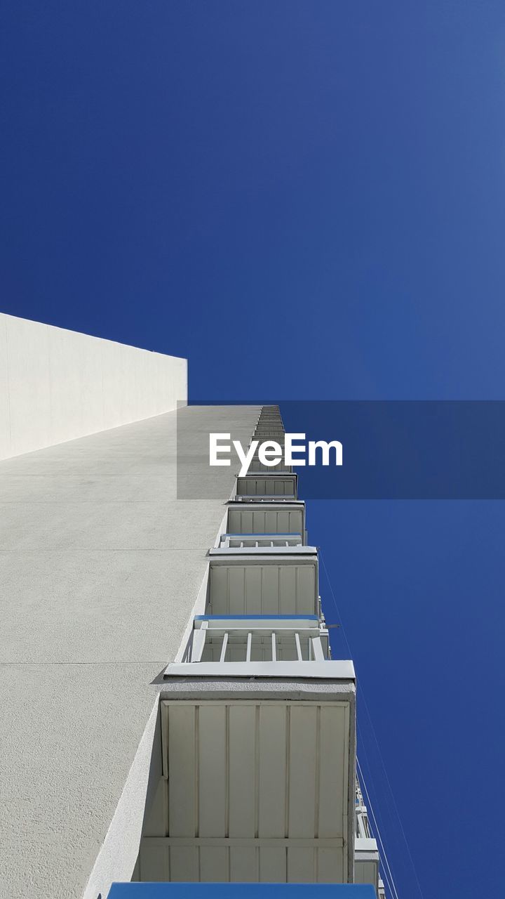 Low angle view of balconies of building against blue sky