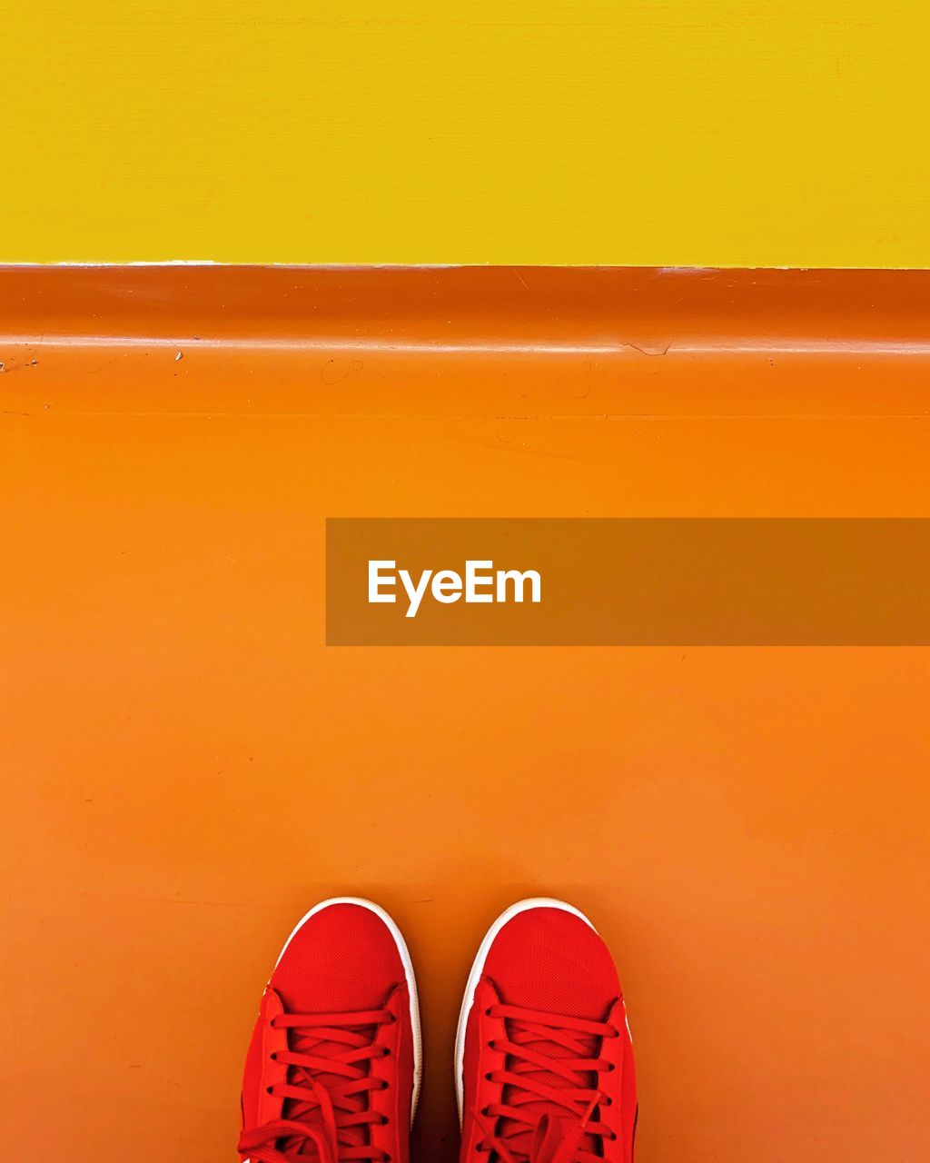 Red shoes on an orange floor with a yellow wall.