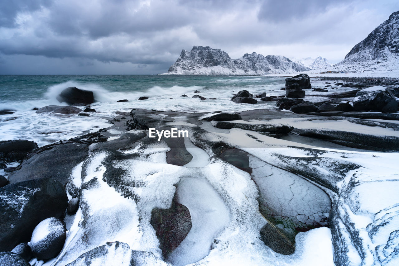 Scenic view of sea and snowcapped mountains against sky