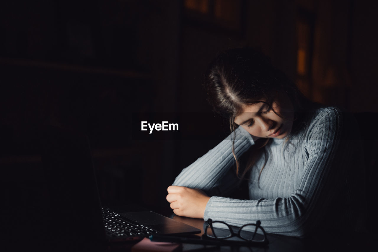 side view of young woman using laptop while sitting at home