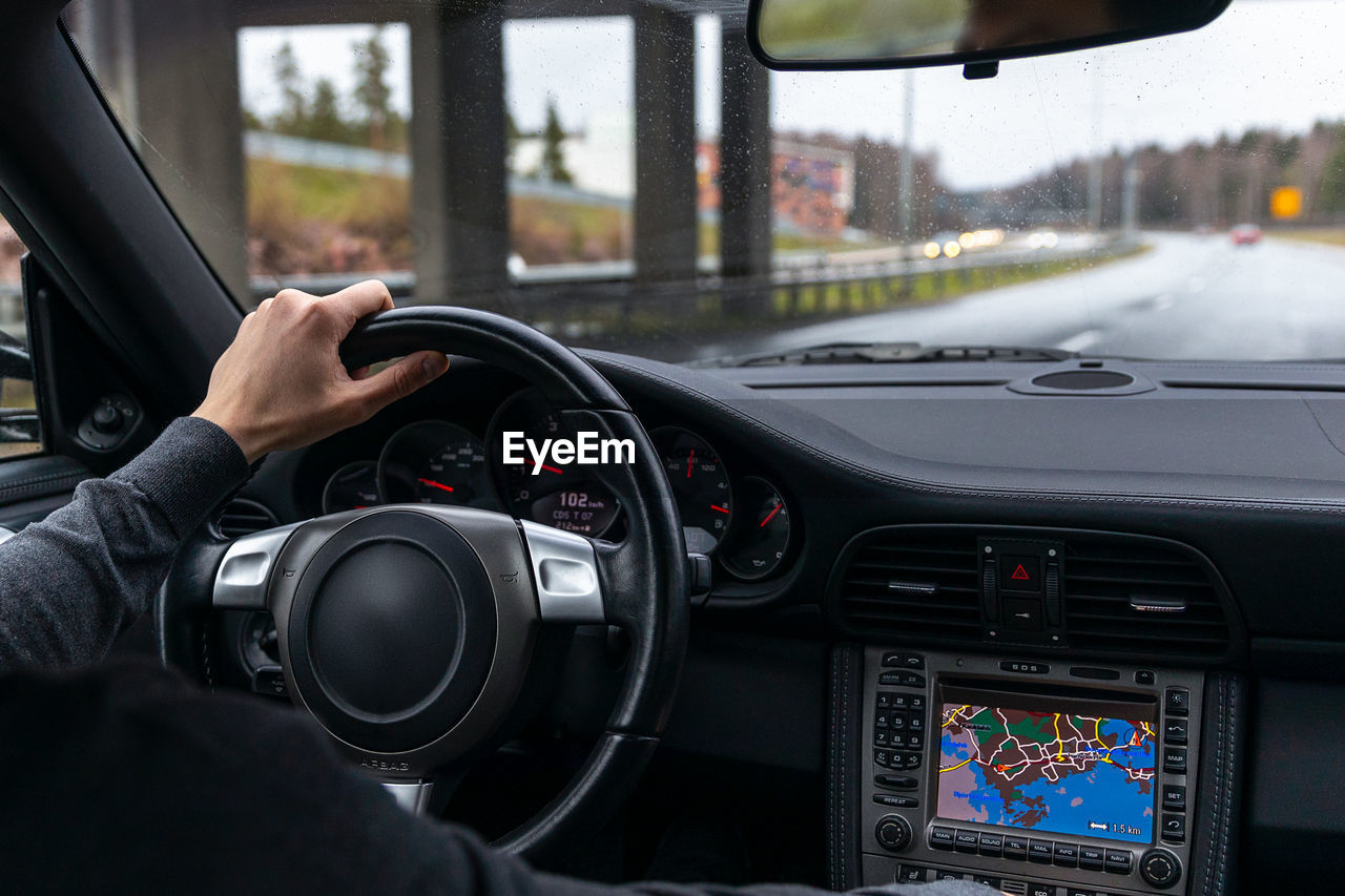 Man drives a car. car interior. steering wheel, shift lever, dashboard. view from the back seat.