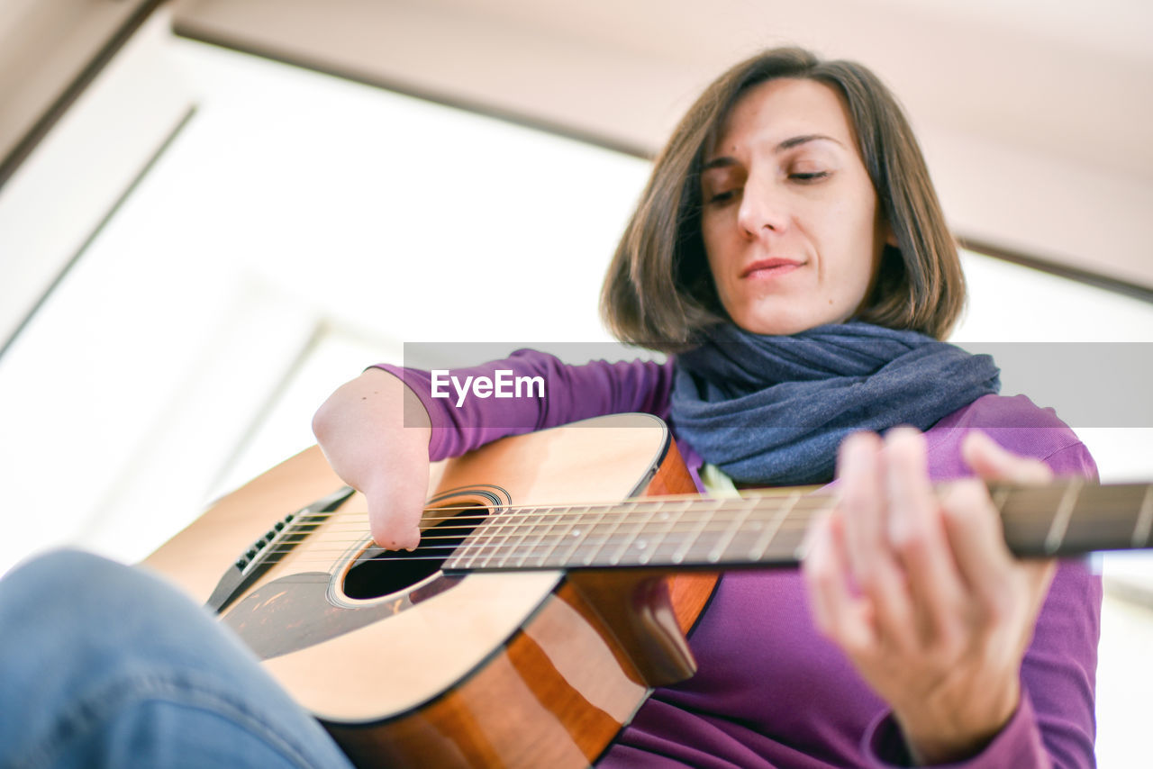 Woman playing guitar at home