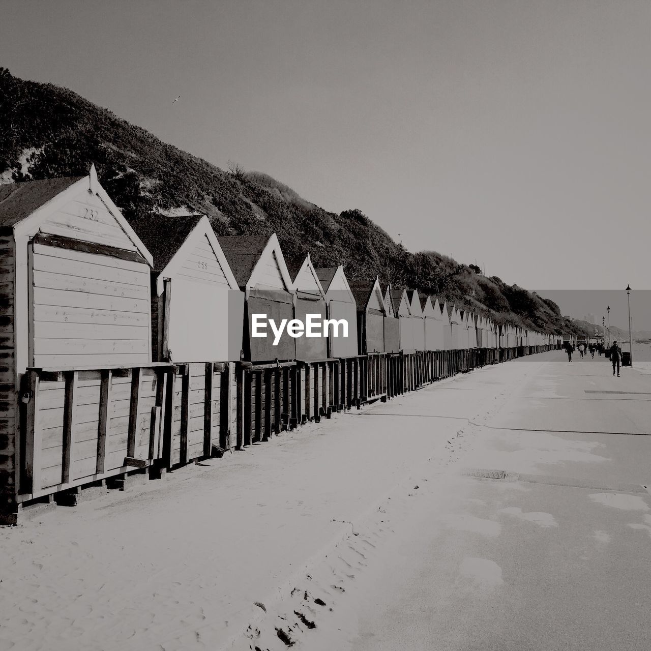 Beach huts by walkway against clear sky