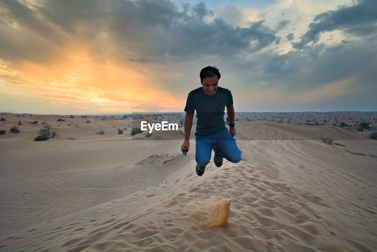 Jumping for joy in the desert on a backdrop of setting skies 