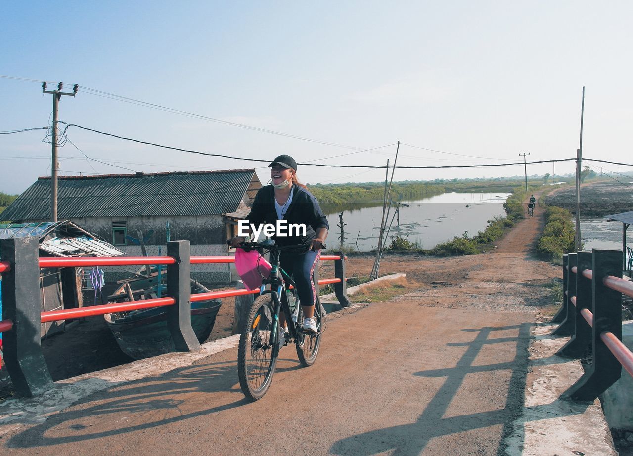 Girl riding bicycle on street against sky