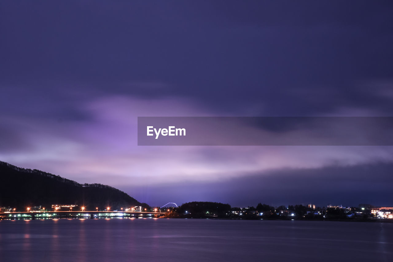 ILLUMINATED CITY BY SEA AT NIGHT