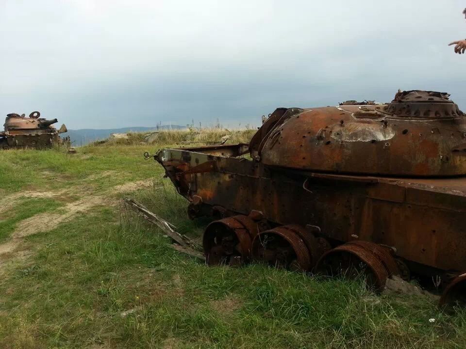 Old armored tanks on grassy field against sky