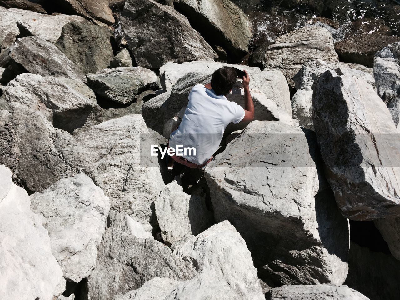 High angle view of man photographing on rocky shore