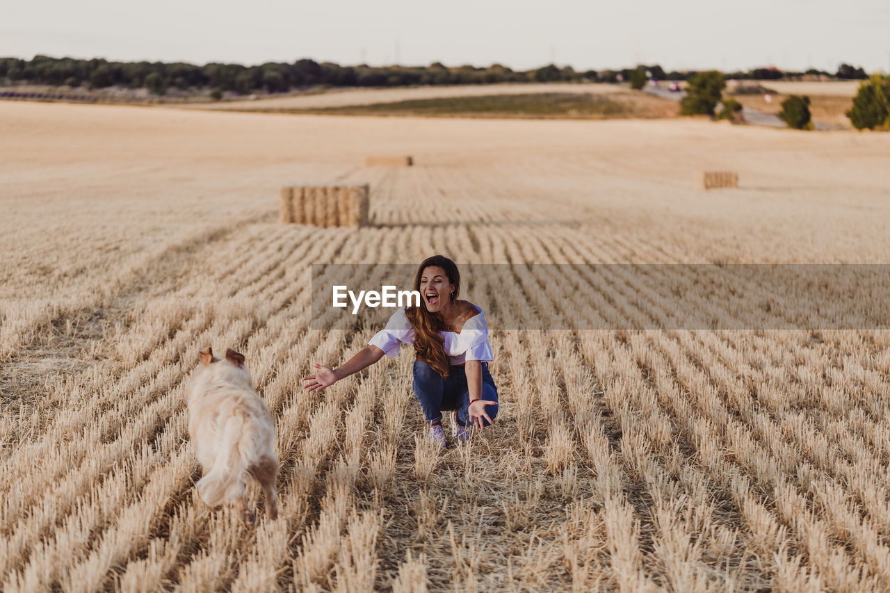 Mid adult woman with dog on agricultural field