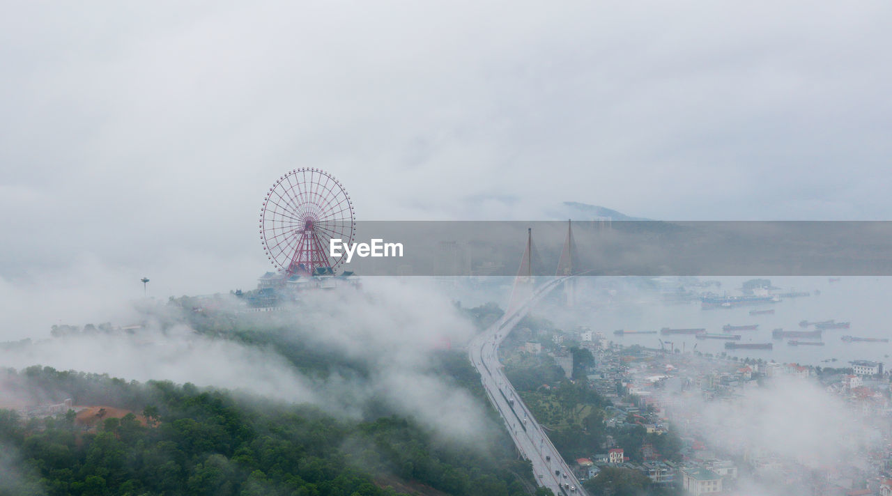 Aerial view of ferris wheel in city during foggy weather