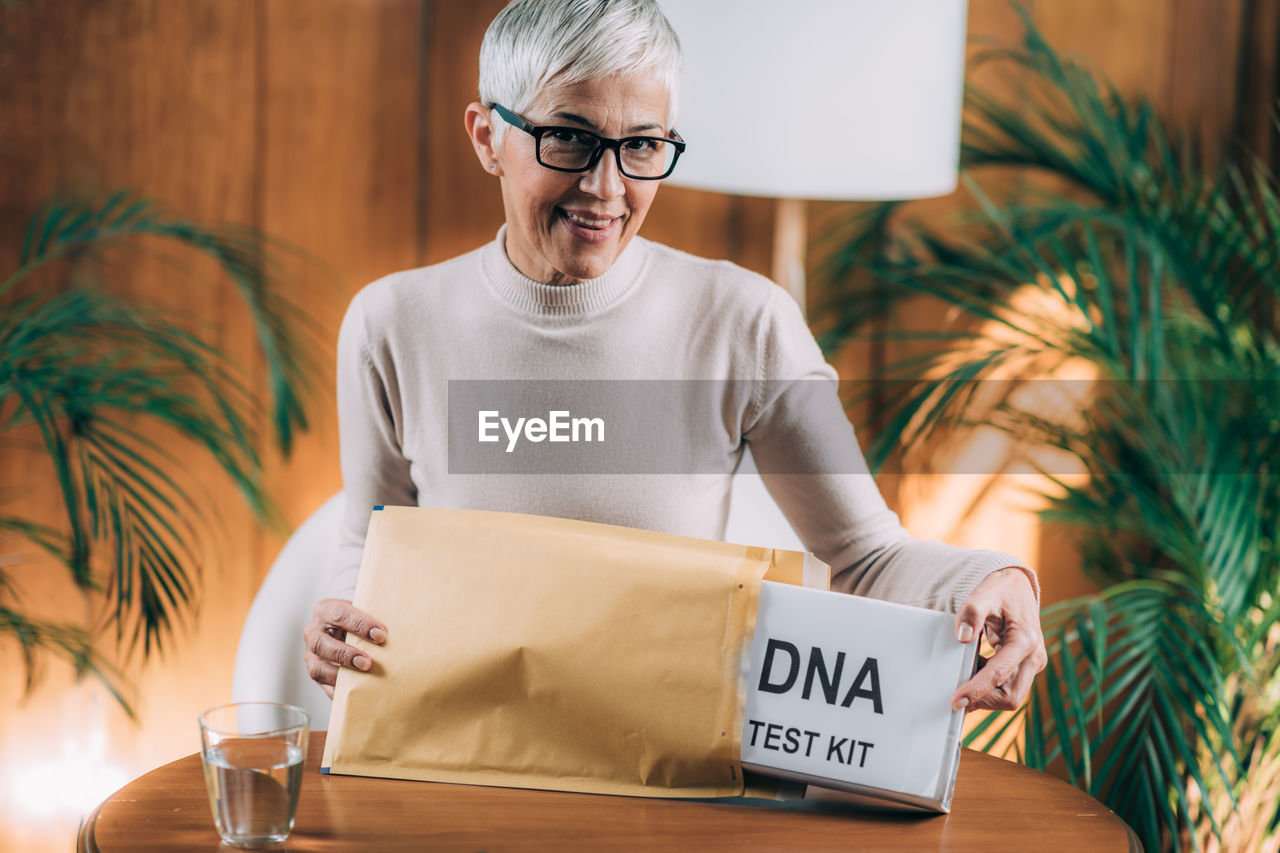 Midsection of woman holding eyeglasses while sitting on table