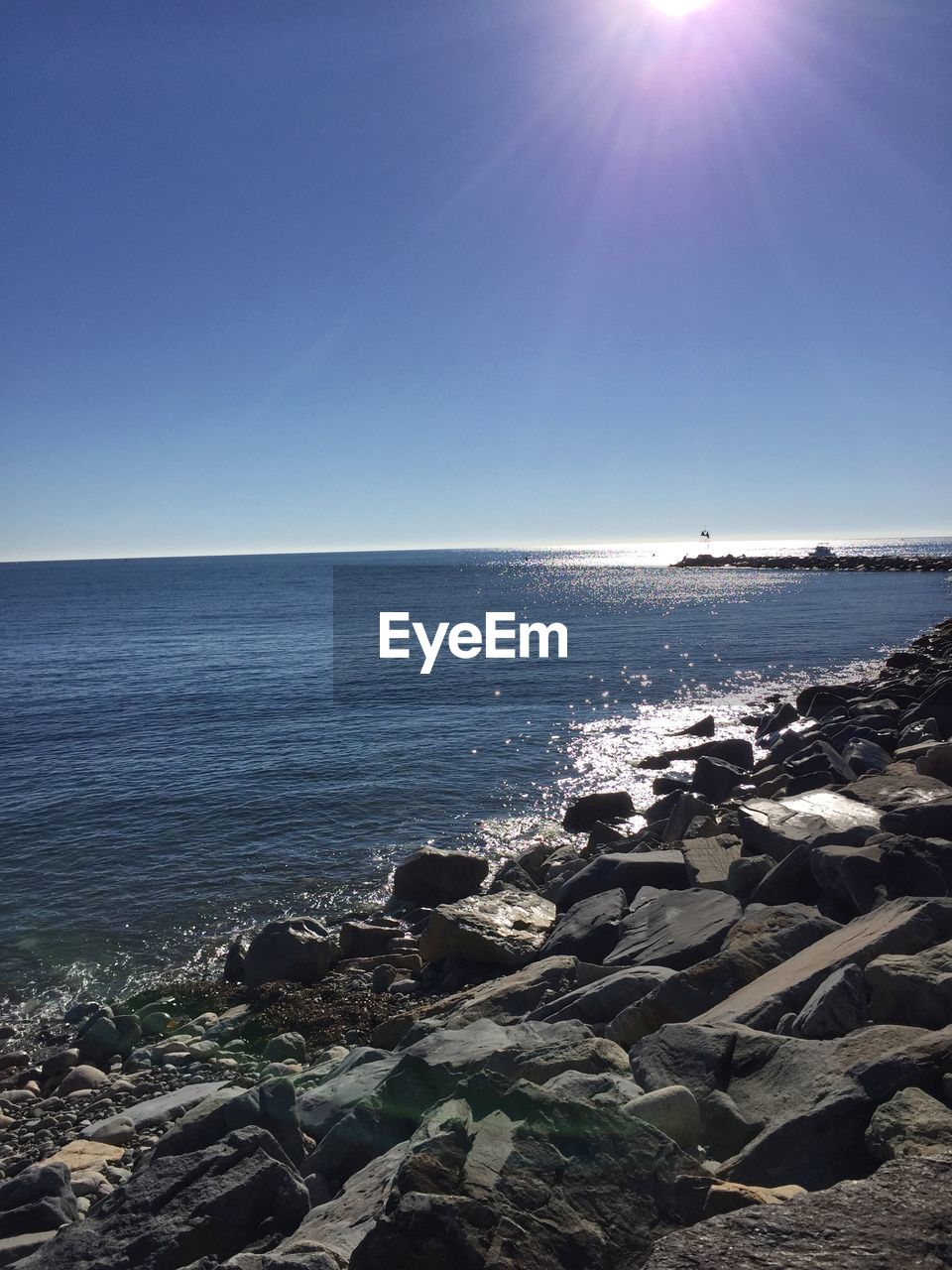 Scenic view of sea and rocky shore against clear sky