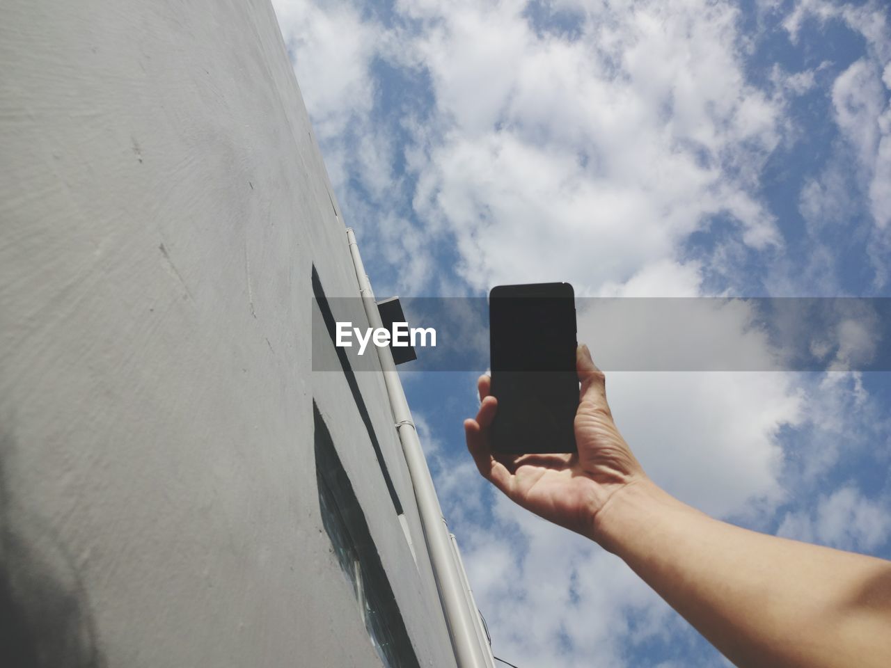 Low angle view of person using mobile phone against sky