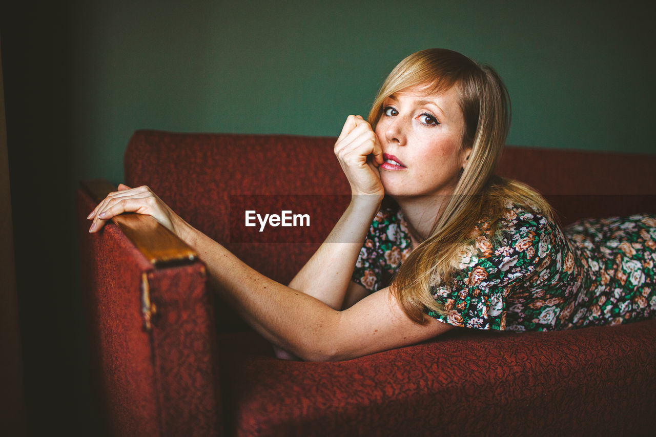 Woman looking away while sitting on sofa