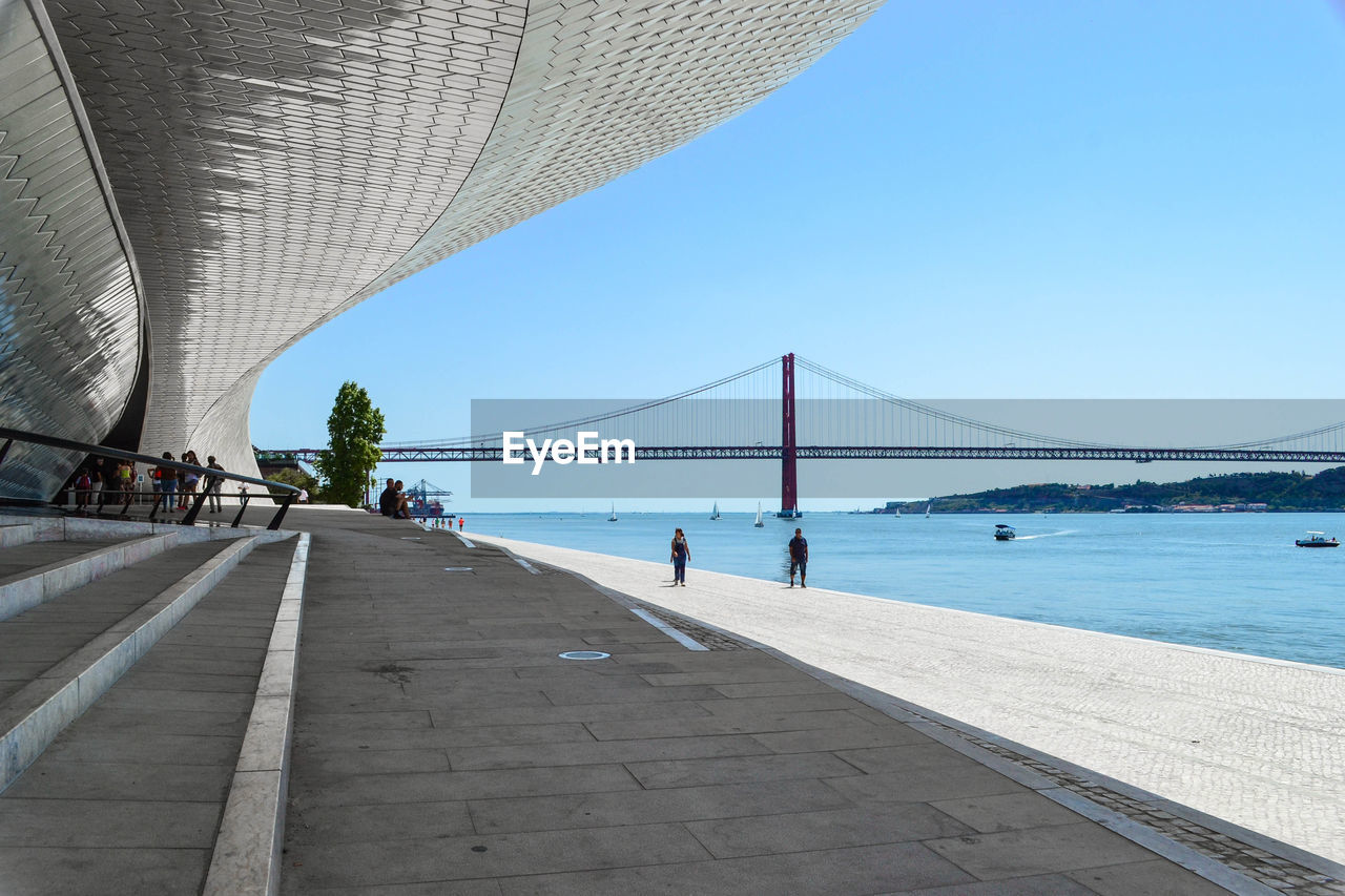 PEOPLE WALKING ON BRIDGE AGAINST SKY