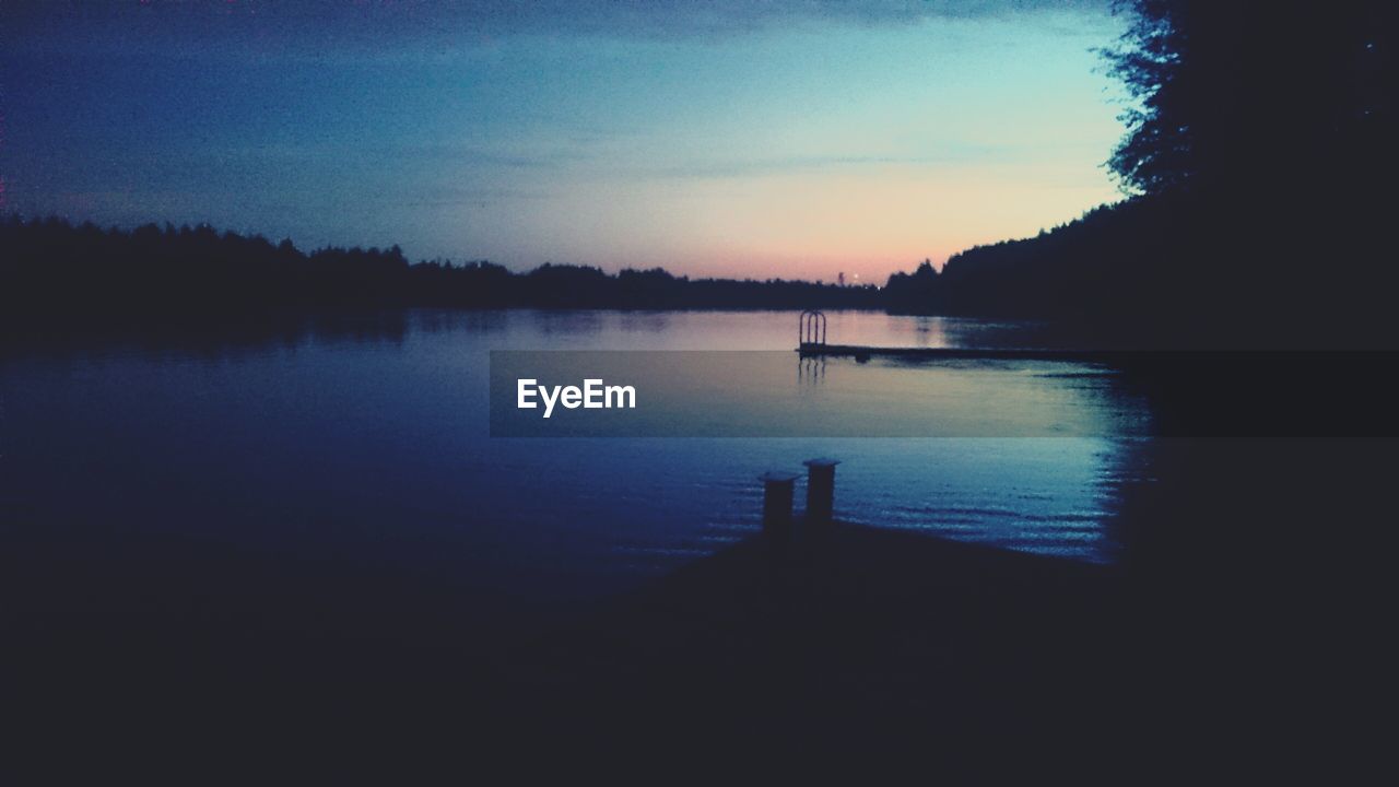 SCENIC VIEW OF CALM LAKE AT SUNSET