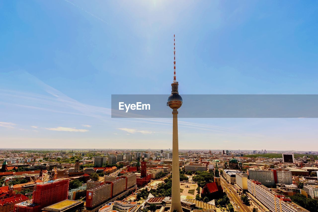 Communications tower in city against sky