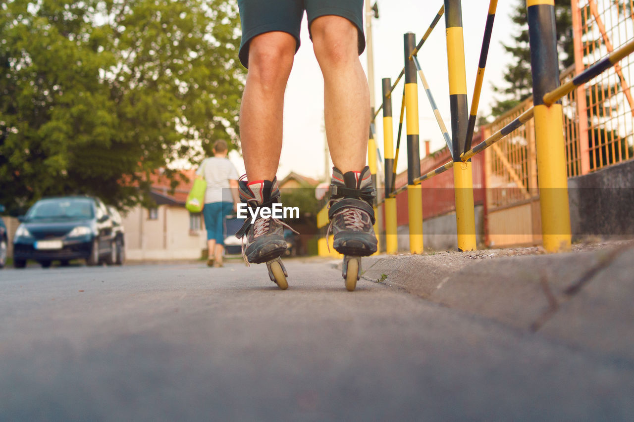 Low section of man roller skating on road in city