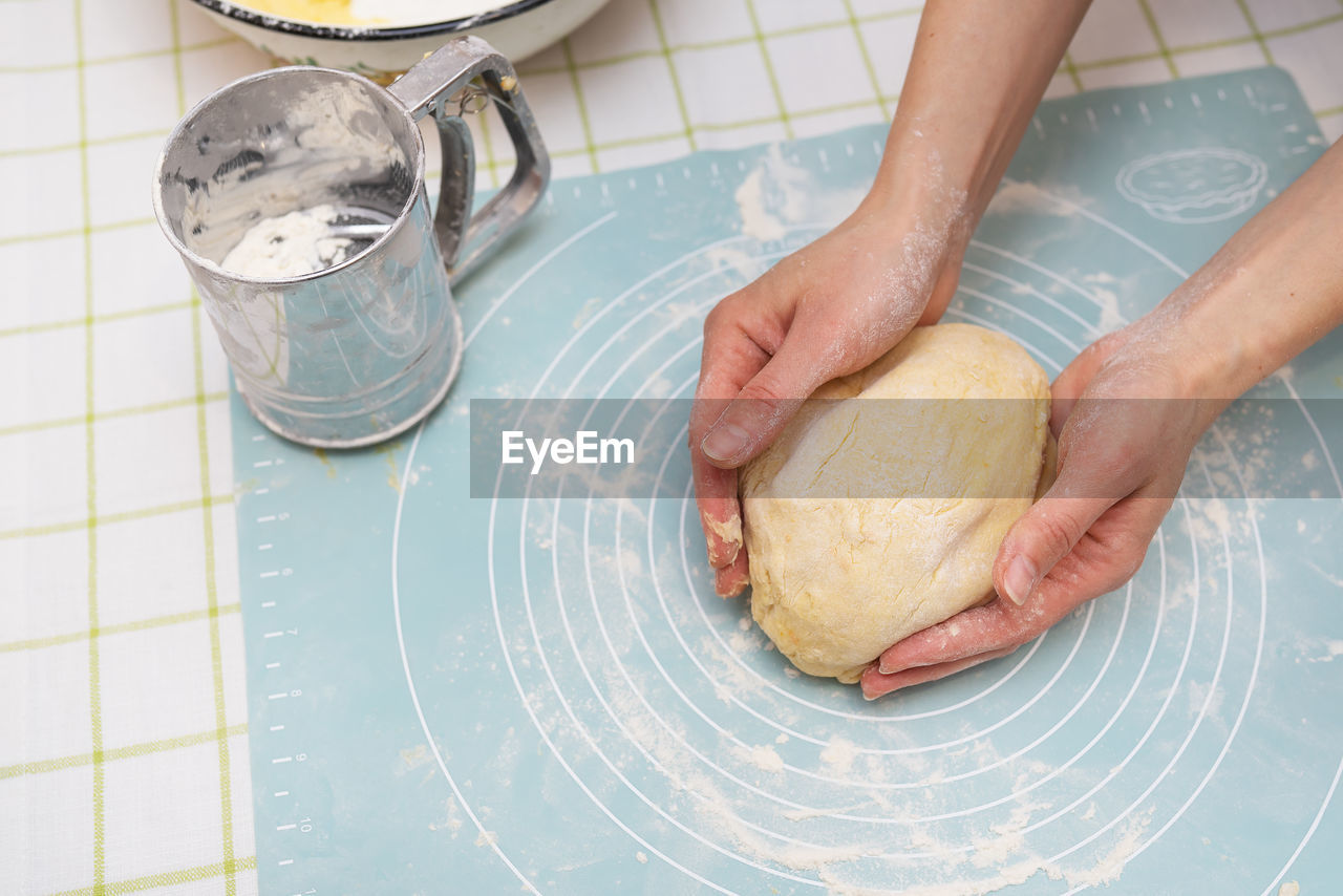 Woman kneading dough with hands, baker's hands, silicone mat, sieve