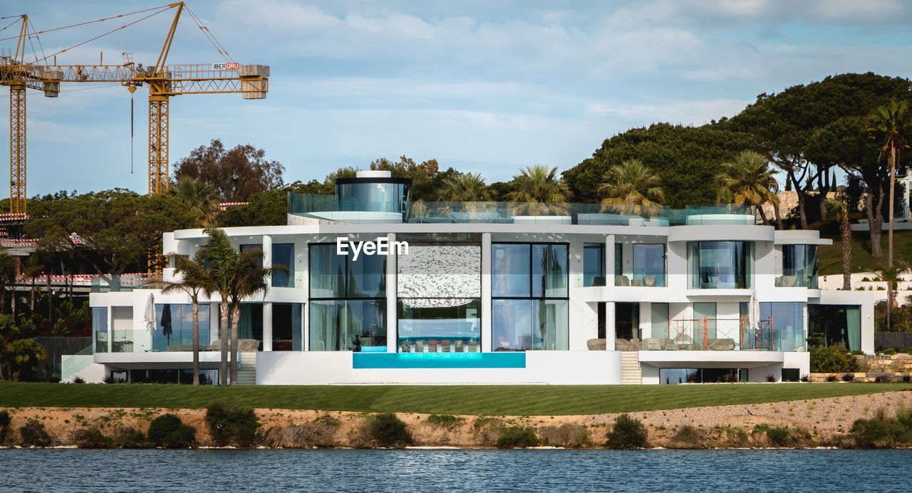 BUILT STRUCTURE BY LAKE AGAINST BUILDING