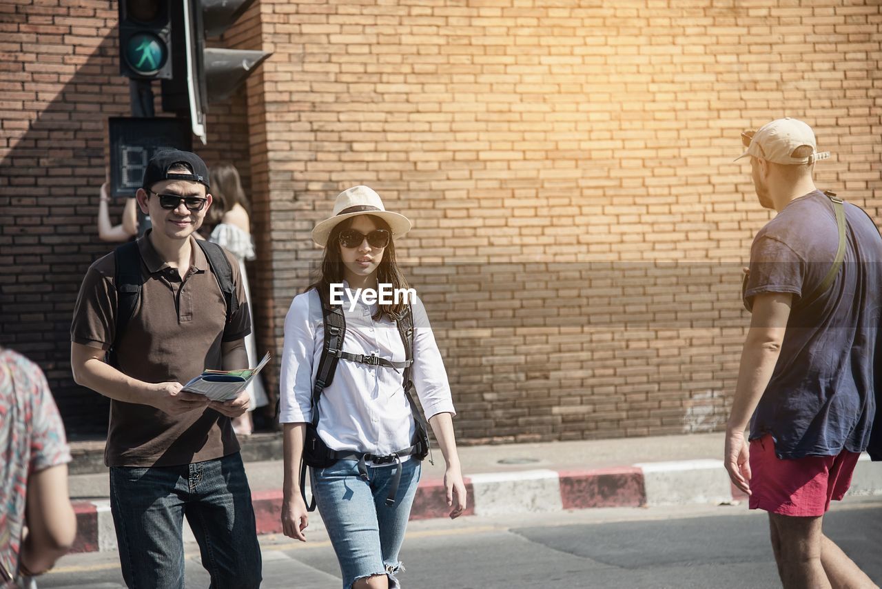 Portrait of couple walking on road against wall