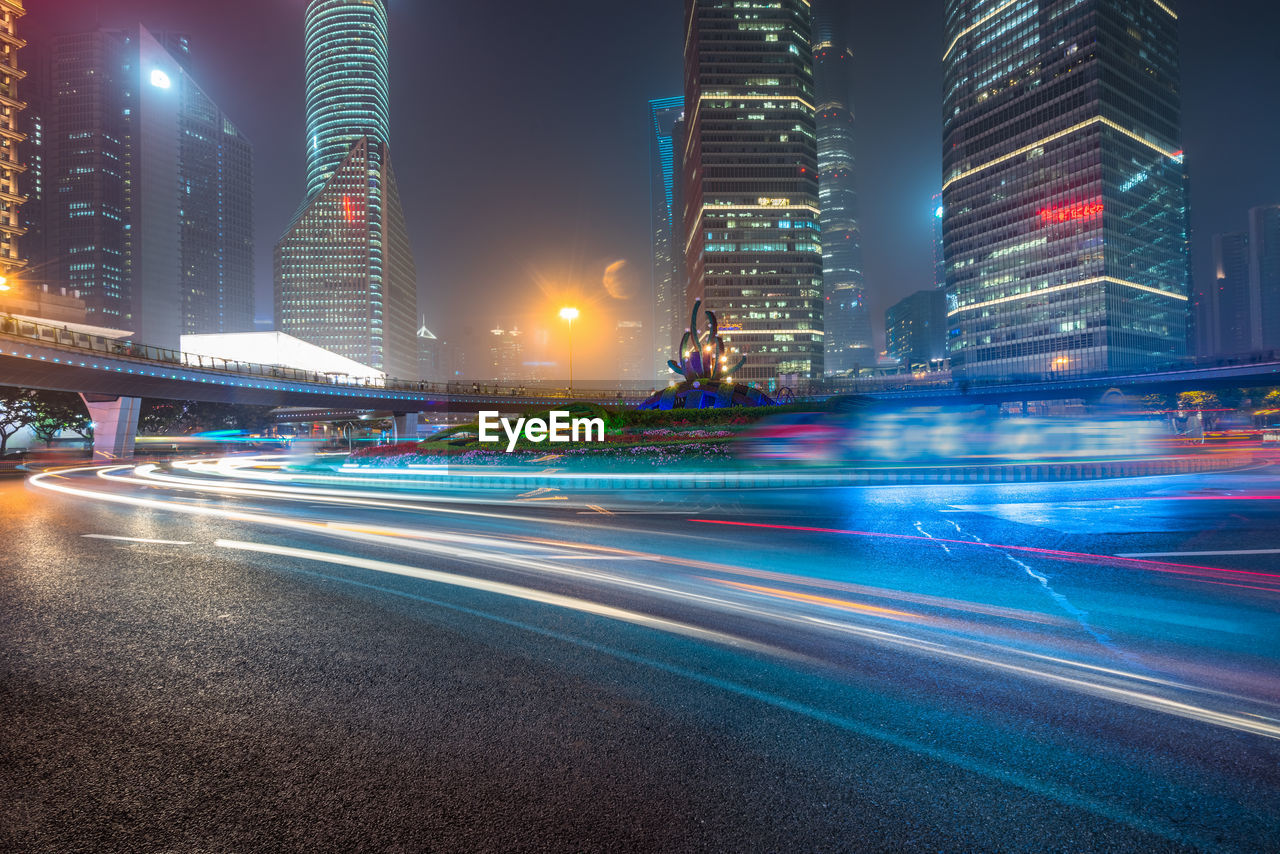 LIGHT TRAILS ON CITY STREET AND ILLUMINATED BUILDINGS AT NIGHT