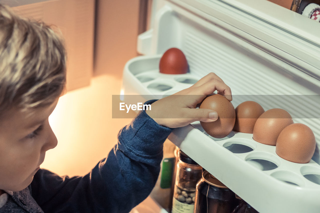 Close-up of boy keeping egg in refrigerator at home