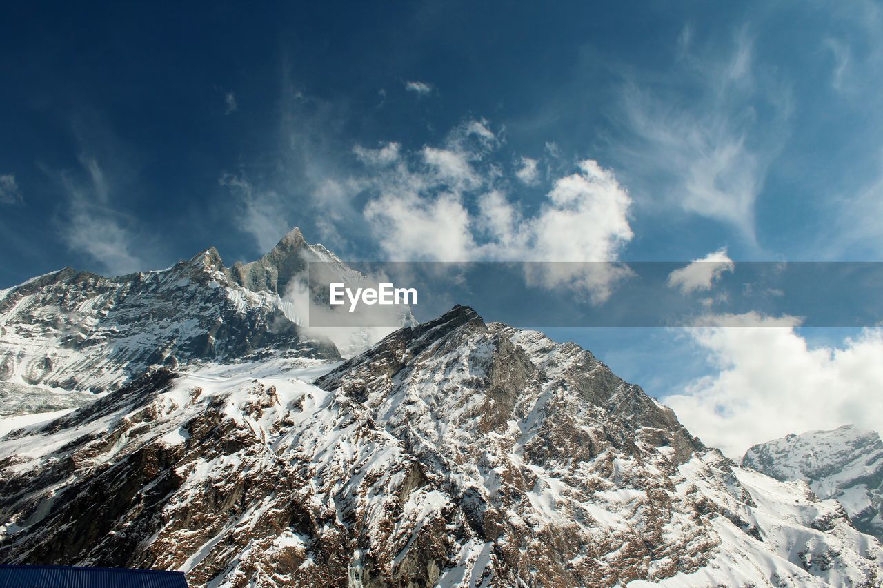 View of snowcapped mountain range against cloudy sky