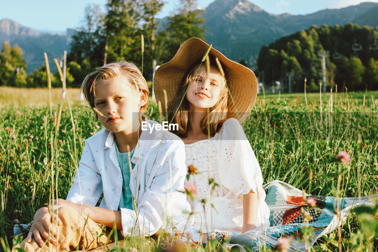 Siblings sitting on field