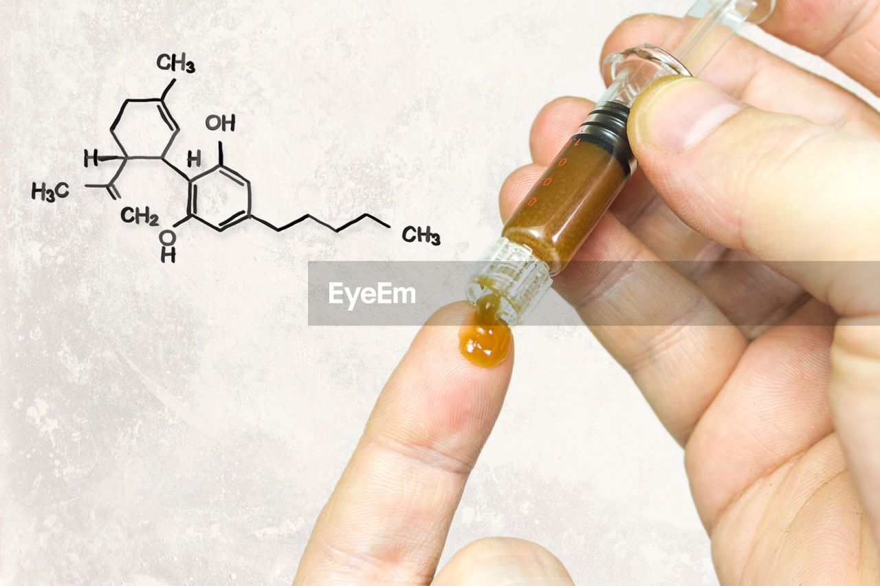 Digital composite image of hand holding medicine in syringe by formulas