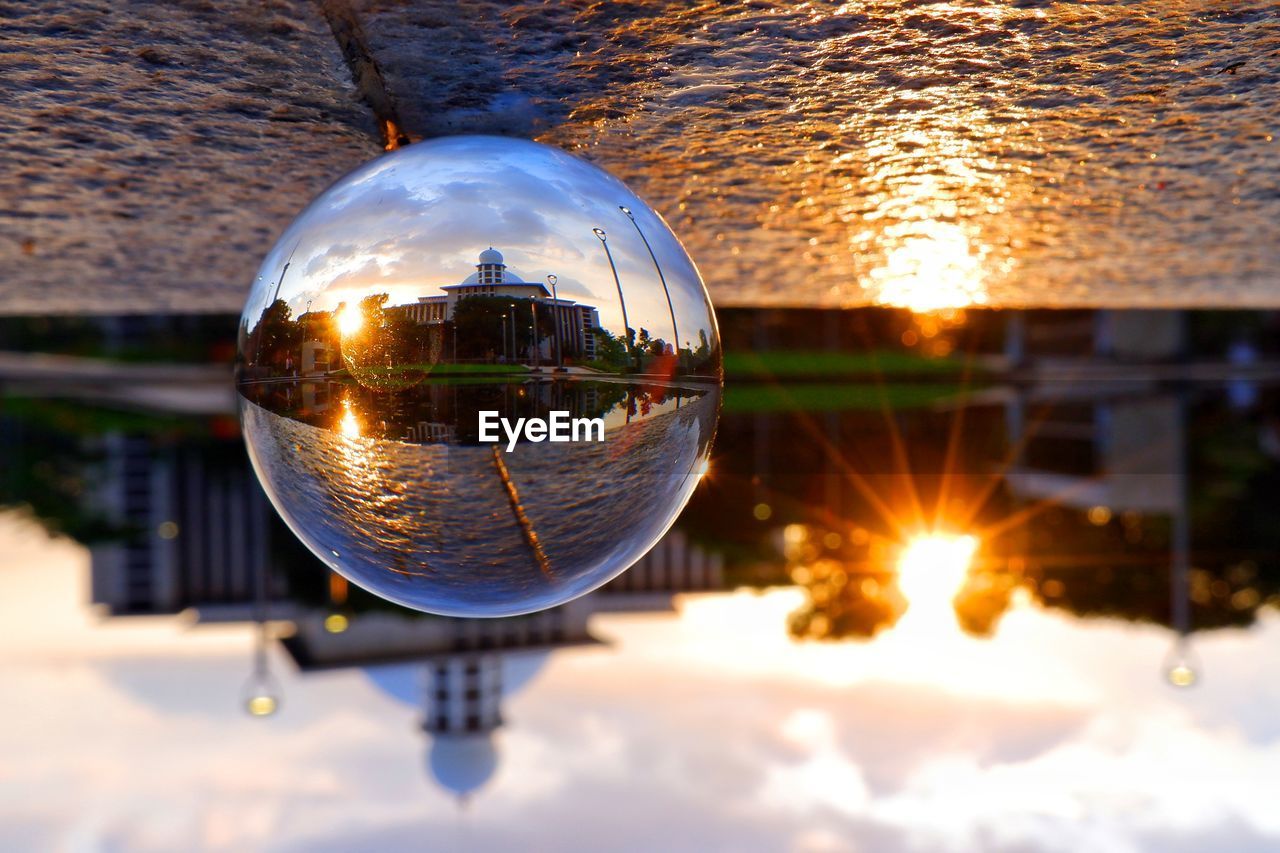 reflection, light, sphere, nature, sky, sunlight, lighting, water, architecture, sunset, no people, cloud, building exterior, outdoors, built structure, city, shiny, illuminated, glass, crystal ball, evening, globe - man made object, travel, environment, building, travel destinations, blue, lake