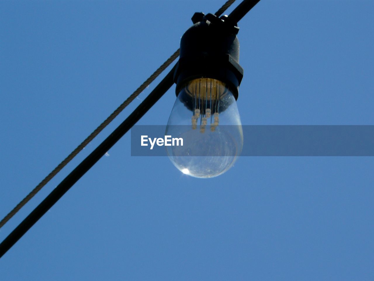 Low angle view of light bulb against blue sky