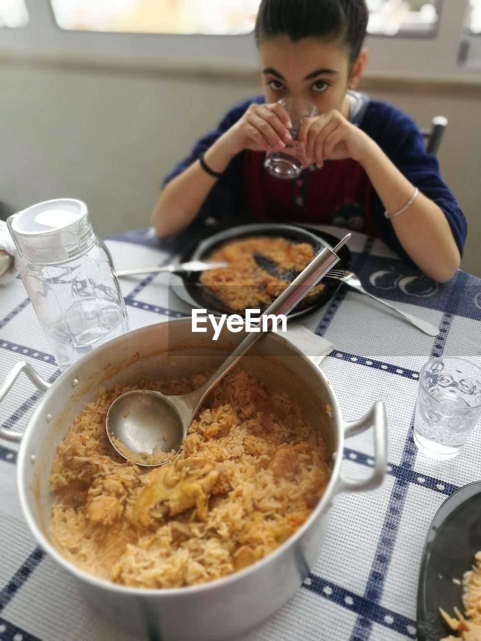 Portrait of girl drinking water while sitting at table