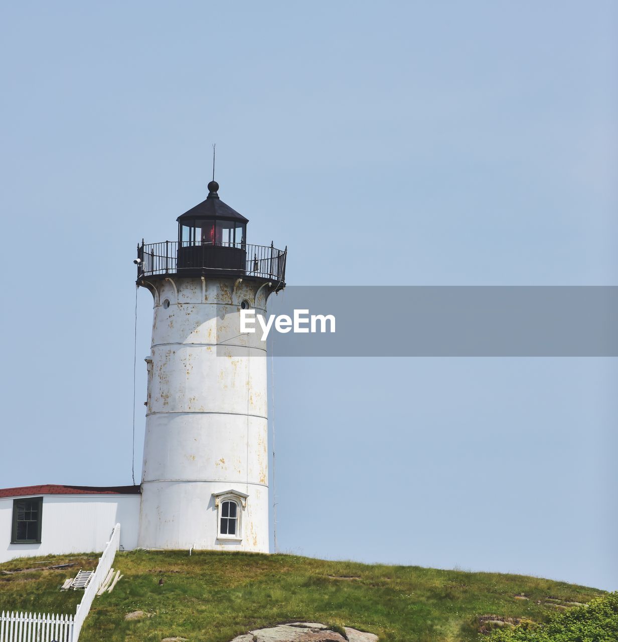 Low angle view of lighthouse by building against clear sky