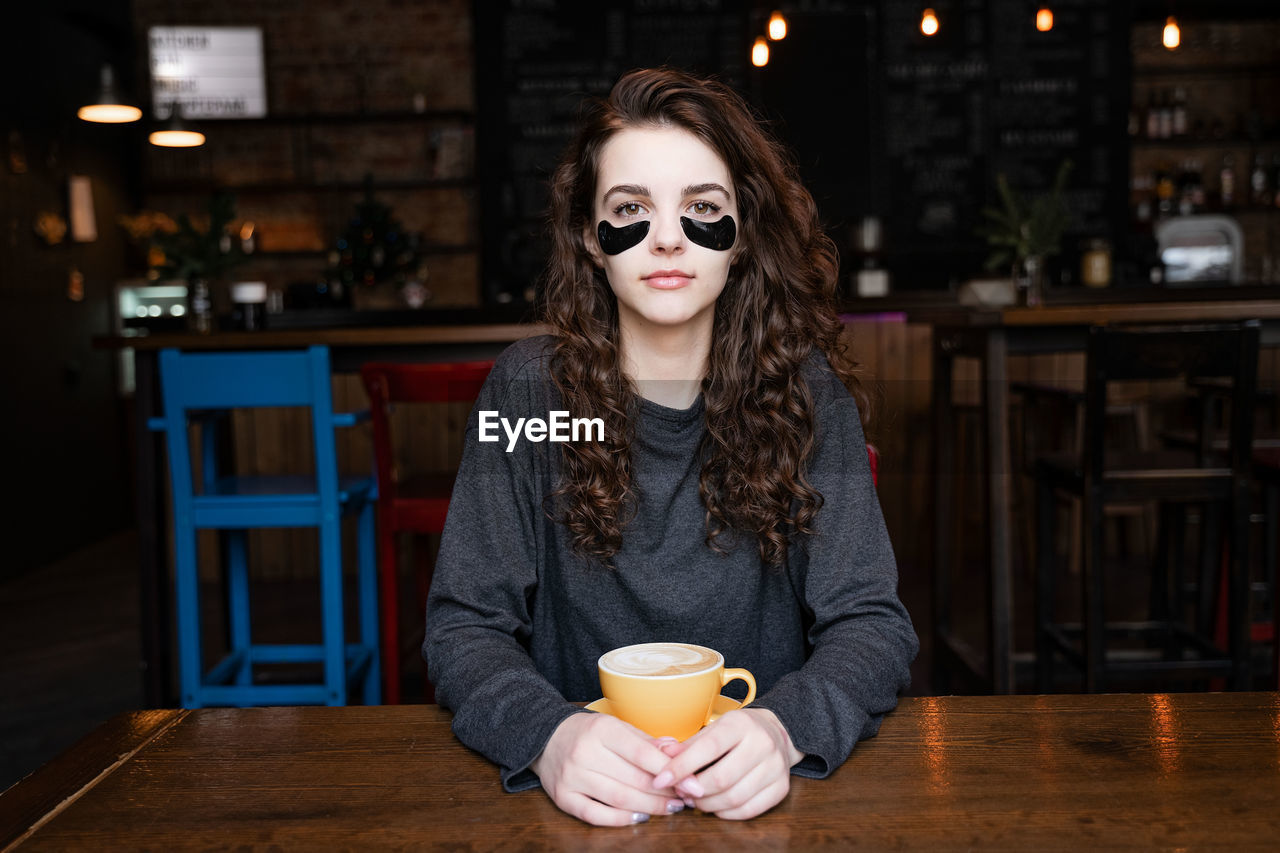 Portrait of young woman drinking coffee at cafe