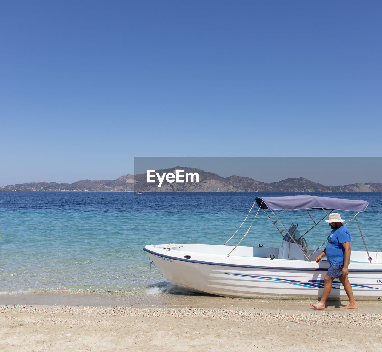 MAN ON SHORE AGAINST CLEAR BLUE SKY