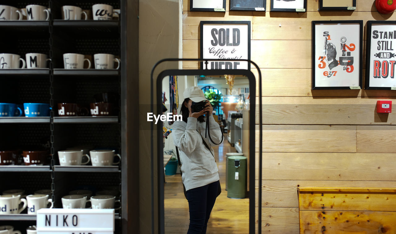 REAR VIEW OF WOMAN STANDING WITH TEXT IN STORE