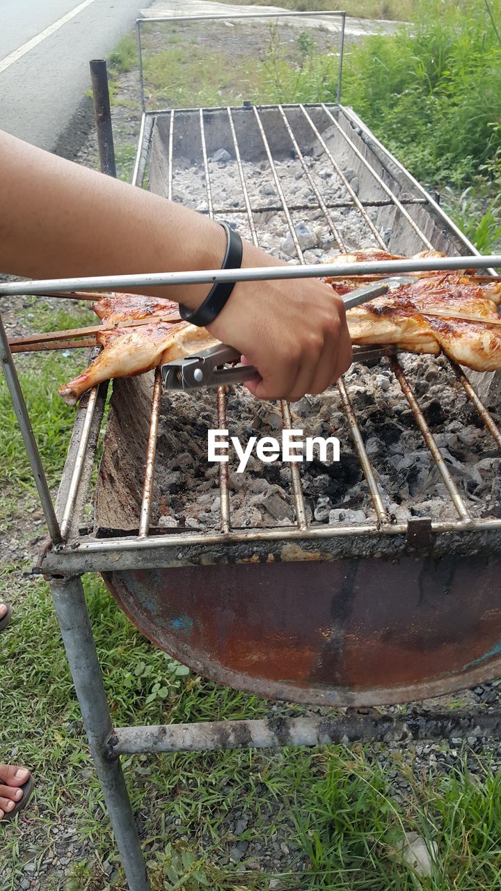 CLOSE-UP OF HAND FEEDING ON BARBECUE
