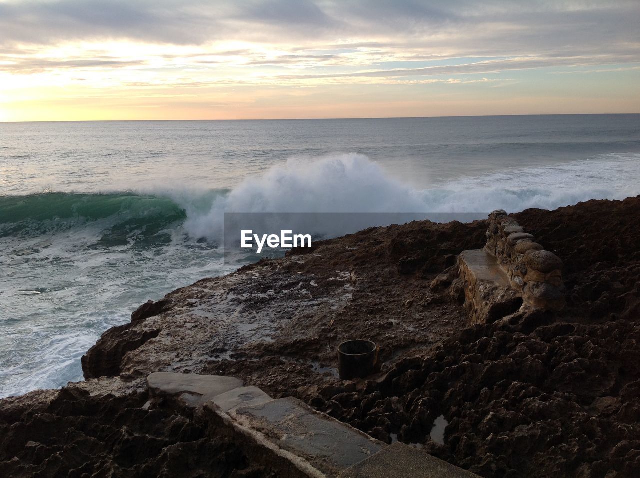 WAVES SPLASHING ON SHORE AGAINST SKY AT SUNSET