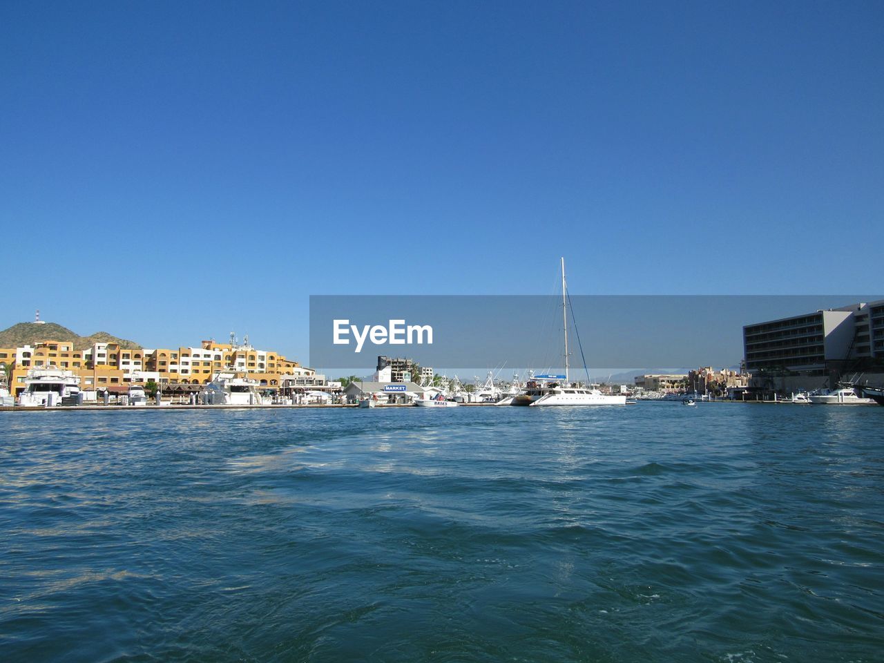 SAILBOATS IN CITY AT WATERFRONT