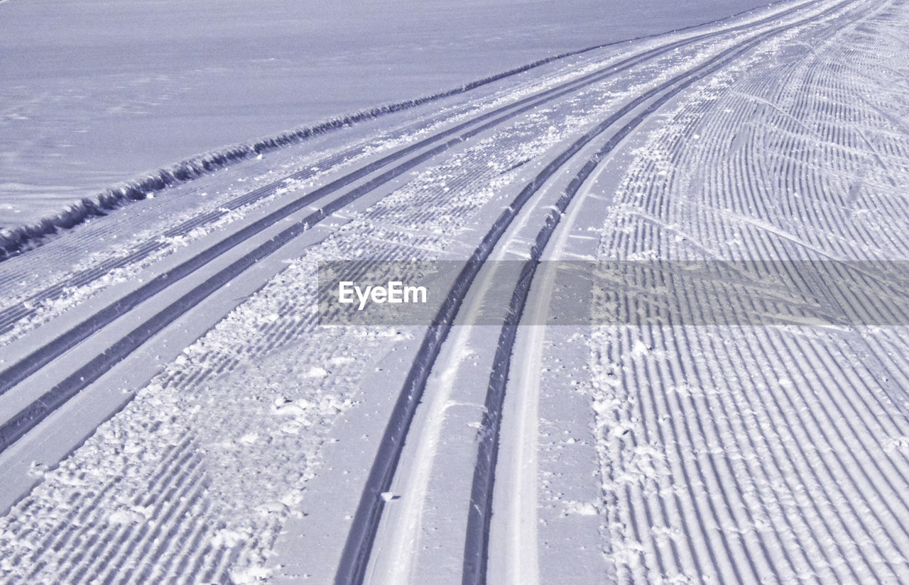 cold temperature, transportation, winter, snow, no people, piste, high angle view, line, nature, white, day, road, landscape, environment, tire track, outdoors, mode of transportation, travel, the way forward, lane, scenics - nature