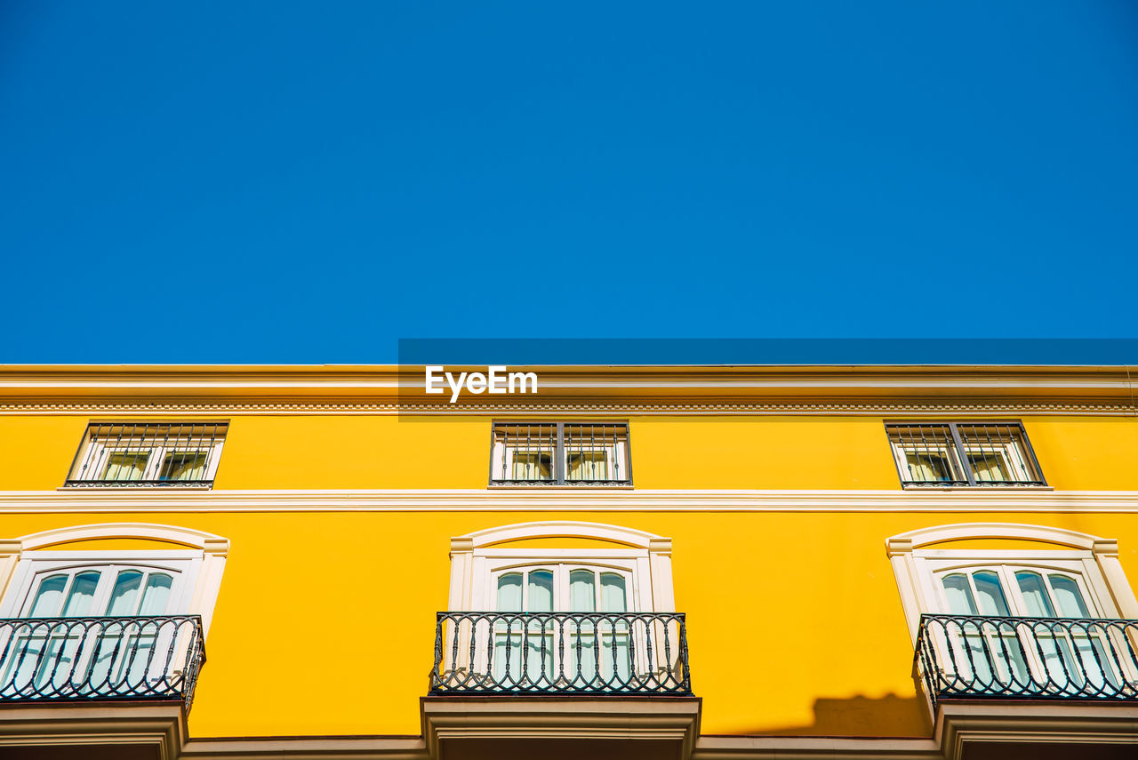 LOW ANGLE VIEW OF YELLOW BUILDING AGAINST SKY