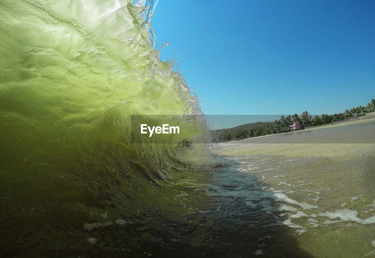 Sea waves flowing against clear blue sky