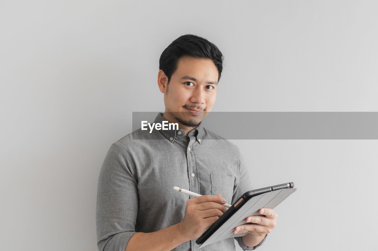 Portrait of businessman using digital tablet against white background