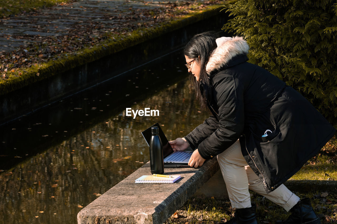 Woman working in the park with laptop. teleworking outdoors due to coronavirus. online business.