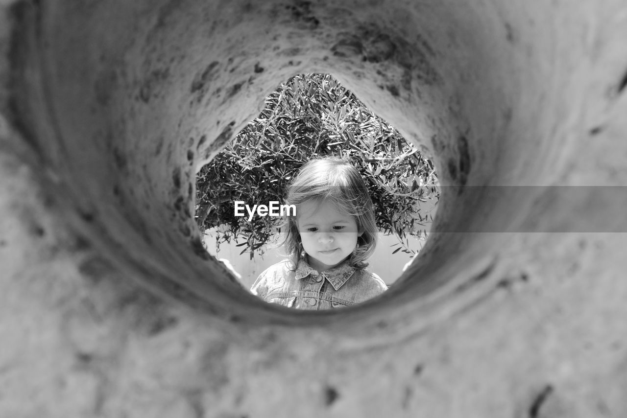 Cute girl looking down seen through hole