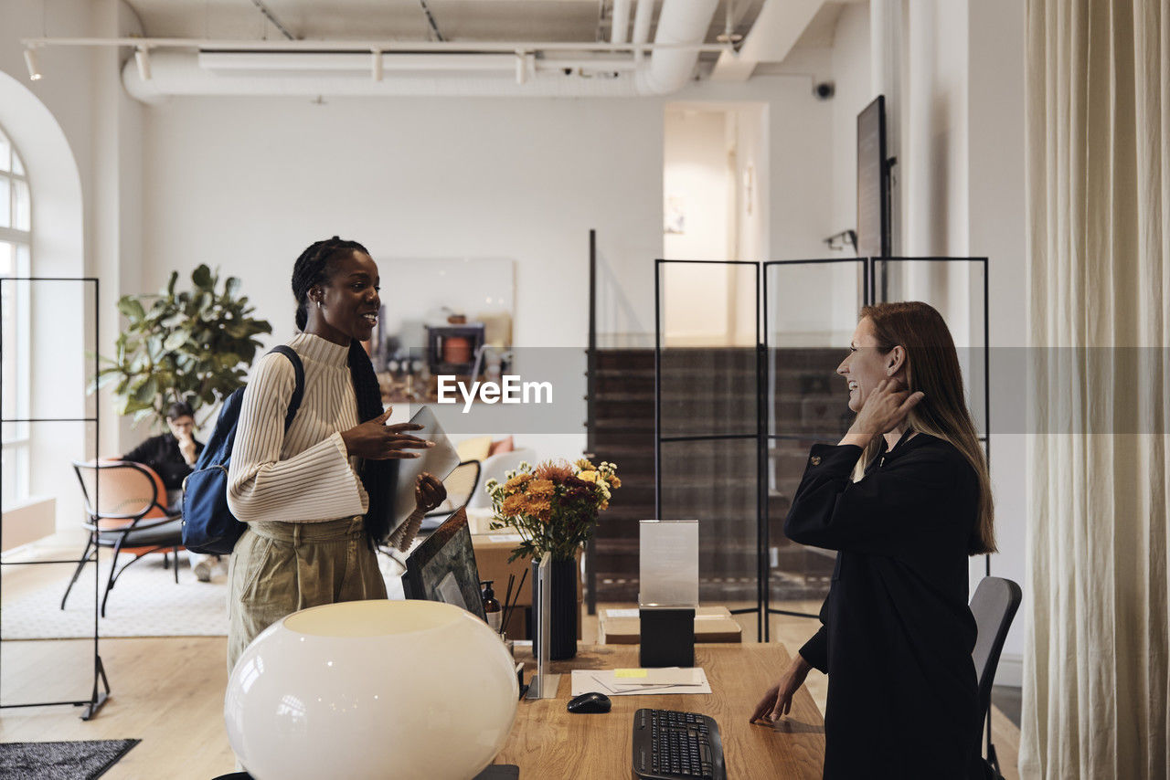 Happy female business professionals greeting each other at coworking office